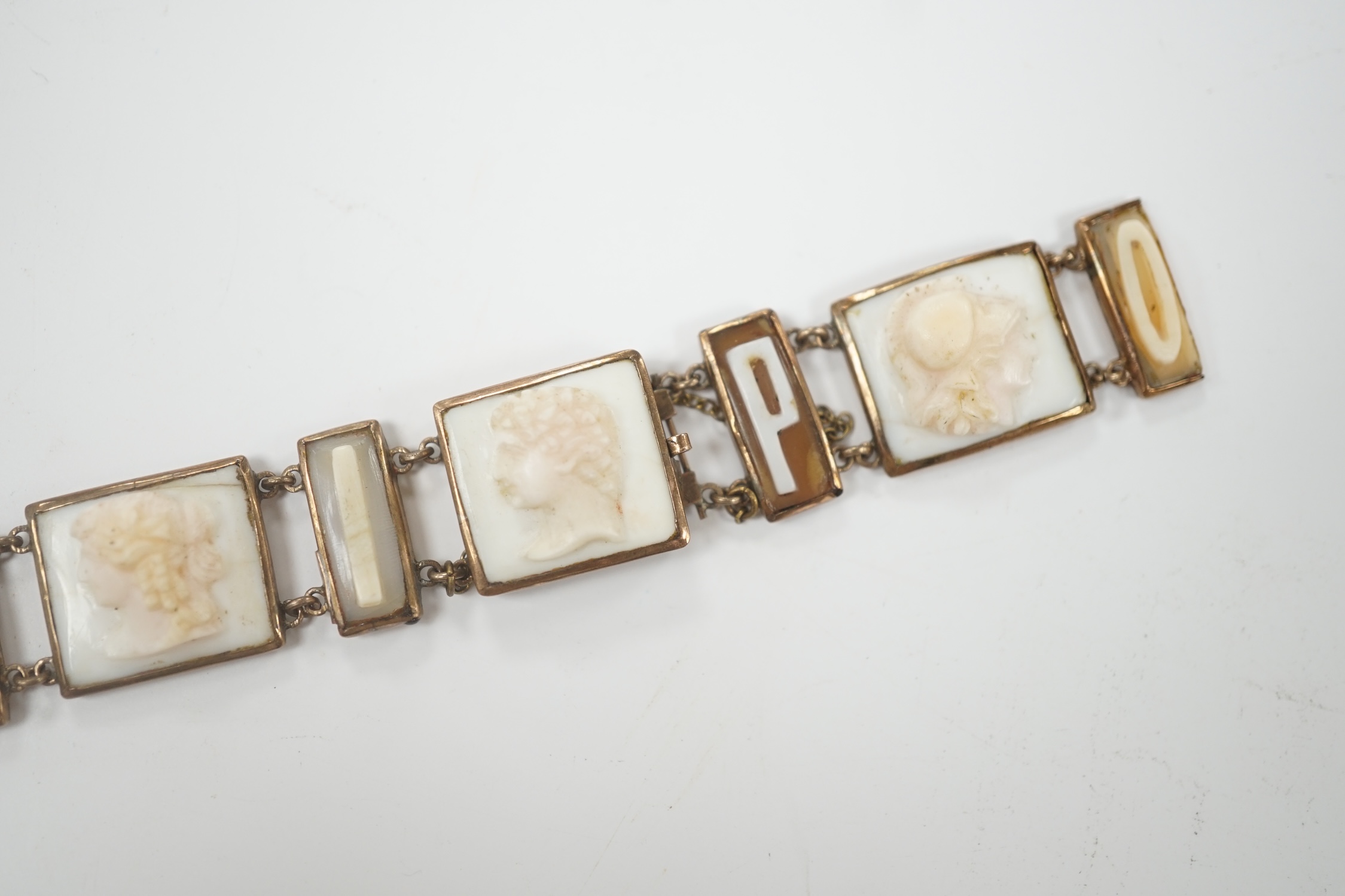 A 19th century Italian? yellow metal overlaid and cameo shell set bracelet, with panels of letters spelling 'Pompei' and panels of busts carved to dexter and sinister, (a.f.), overall 16.8cm.